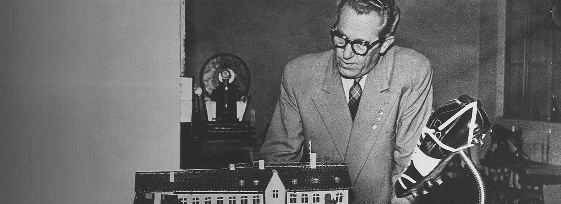 Rudolf Dassler blickt auf ein Miniatur-Haus